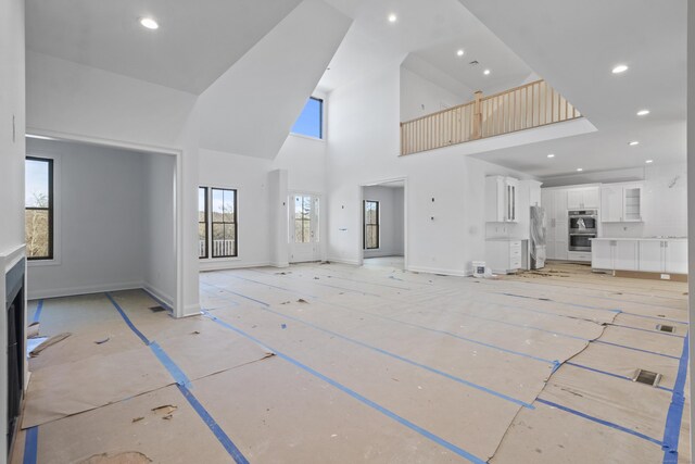 unfurnished living room with a fireplace and a high ceiling