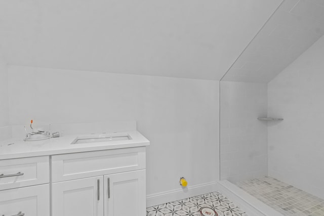 bathroom featuring vanity, a tile shower, and lofted ceiling