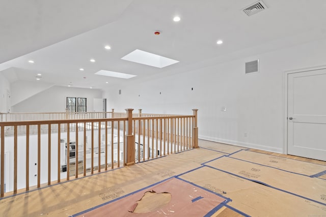 unfurnished room featuring vaulted ceiling with skylight, baseboards, visible vents, and recessed lighting