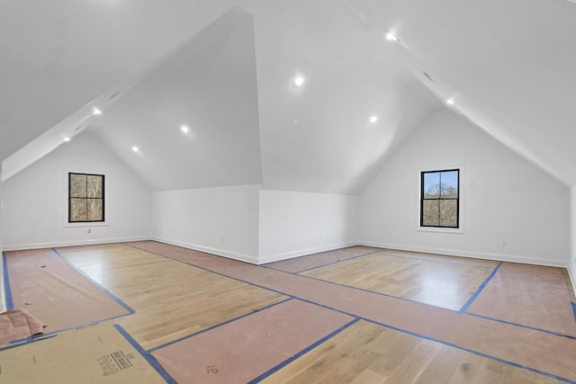 additional living space with basketball hoop, lofted ceiling, baseboards, and wood finished floors