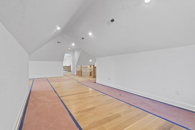 bonus room with light wood-type flooring, visible vents, vaulted ceiling, and baseboards