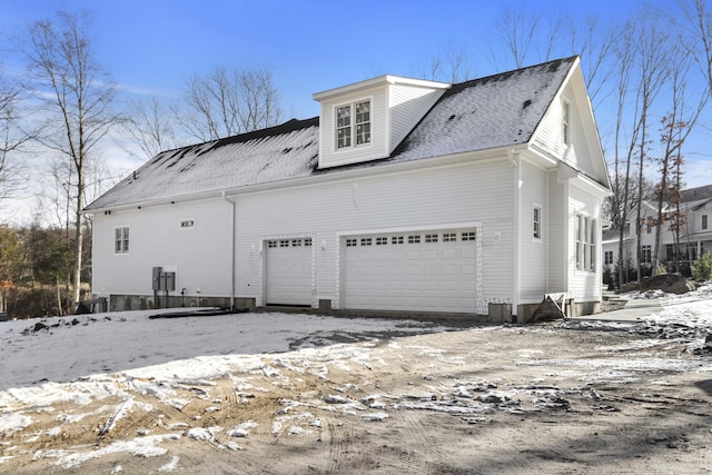 snow covered property with a garage