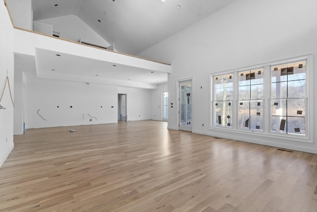 unfurnished living room with light hardwood / wood-style floors and high vaulted ceiling