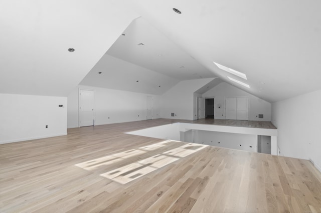 additional living space with light hardwood / wood-style floors and lofted ceiling with skylight