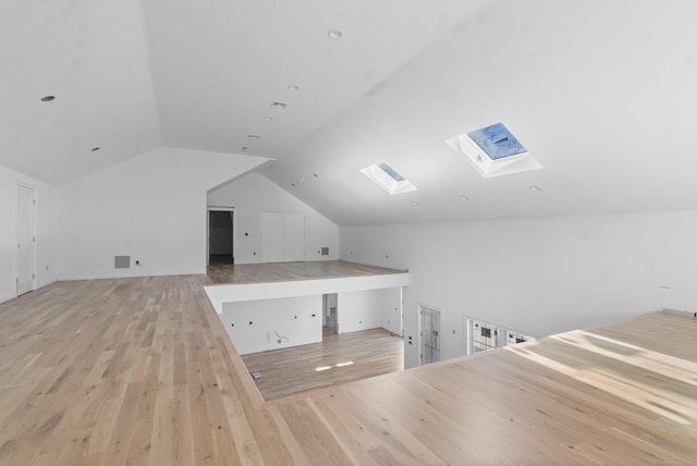 additional living space with light wood-type flooring and vaulted ceiling with skylight