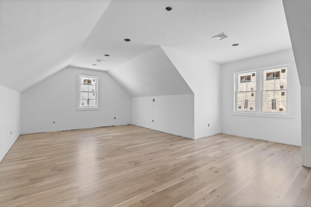 bonus room with light wood-type flooring and vaulted ceiling