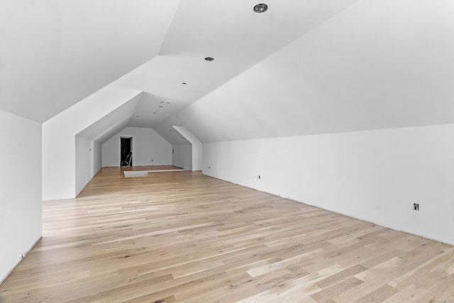 additional living space featuring light wood-type flooring and vaulted ceiling