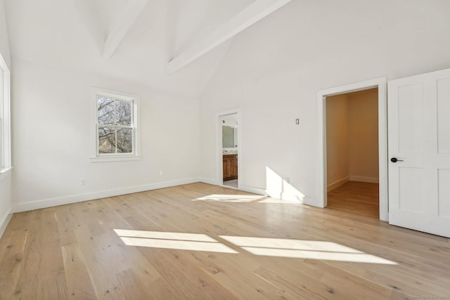 empty room featuring light hardwood / wood-style floors, beam ceiling, and high vaulted ceiling