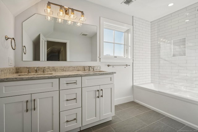 bathroom with tile patterned floors, vanity, and tiled shower / bath