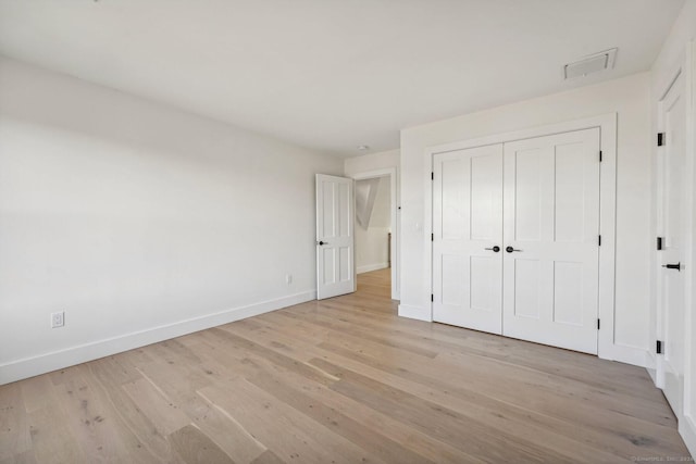 unfurnished bedroom with a closet and light wood-type flooring