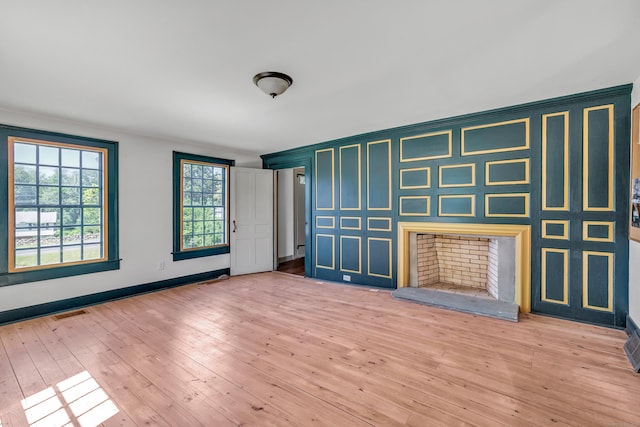 unfurnished living room with a baseboard heating unit and light wood-type flooring