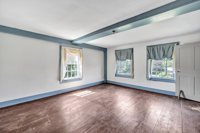 spare room with beam ceiling, plenty of natural light, and dark wood-type flooring