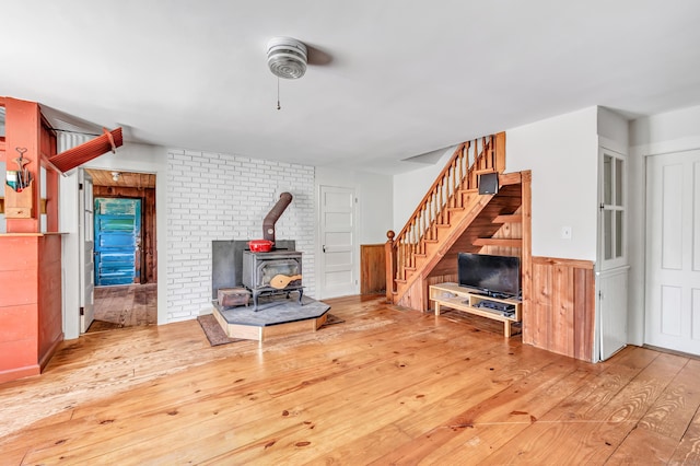 living room featuring hardwood / wood-style flooring, a wood stove, and wood walls