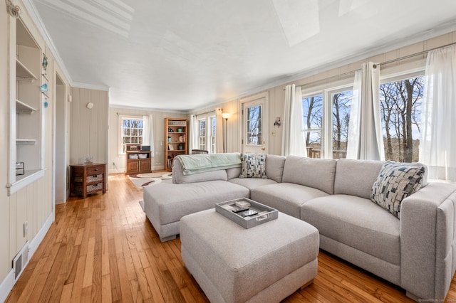 living room with built in shelves, ornamental molding, and light hardwood / wood-style flooring