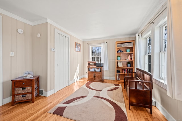 living area with built in features, light hardwood / wood-style floors, and crown molding