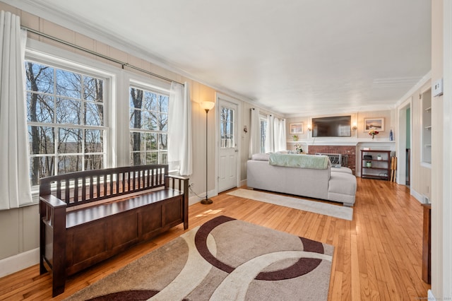 bedroom featuring light hardwood / wood-style floors, a brick fireplace, and crown molding