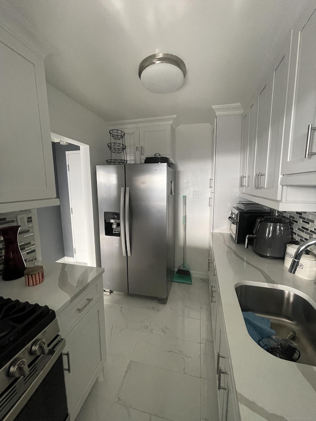 kitchen with white cabinets, appliances with stainless steel finishes, tasteful backsplash, and sink