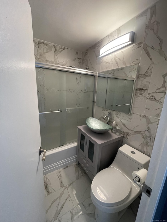 full bathroom featuring vanity, enclosed tub / shower combo, tile walls, and toilet