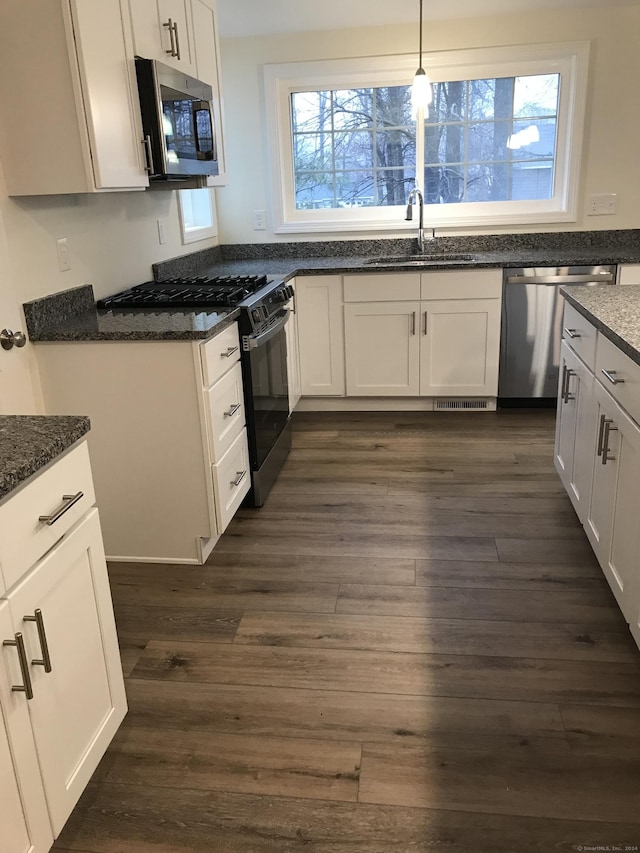 kitchen with stainless steel appliances, white cabinetry, hanging light fixtures, and sink