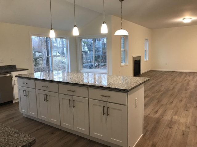 kitchen with white cabinets, stainless steel dishwasher, hanging light fixtures, and light stone counters