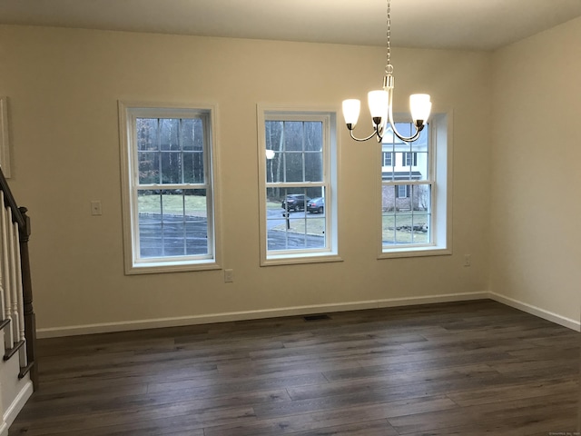 unfurnished dining area with dark wood-type flooring and an inviting chandelier