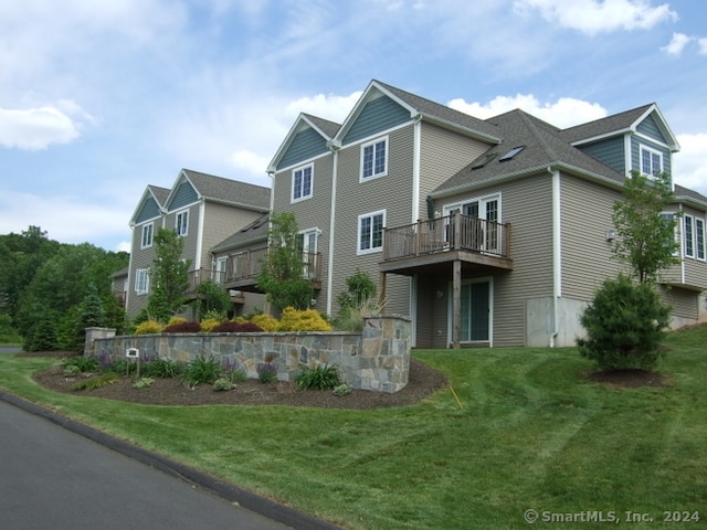 view of front of house with a balcony and a front yard