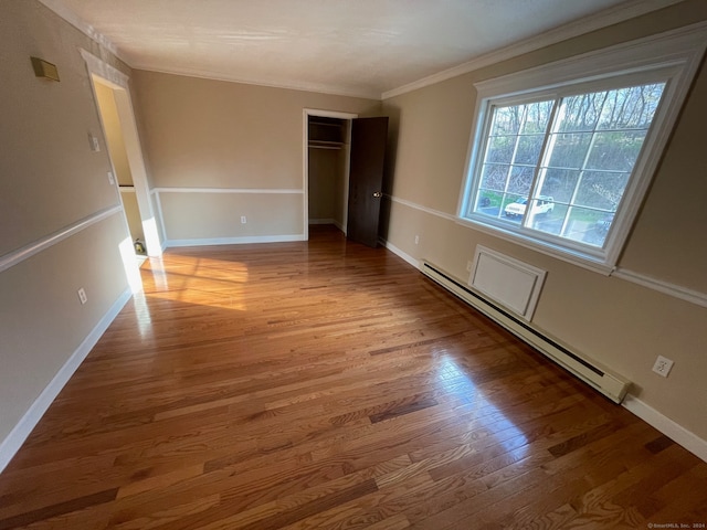 spare room with ornamental molding, hardwood / wood-style floors, and baseboard heating