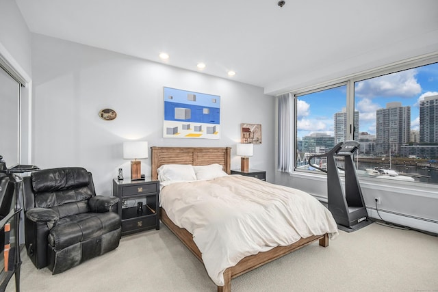 bedroom with baseboard heating and light carpet