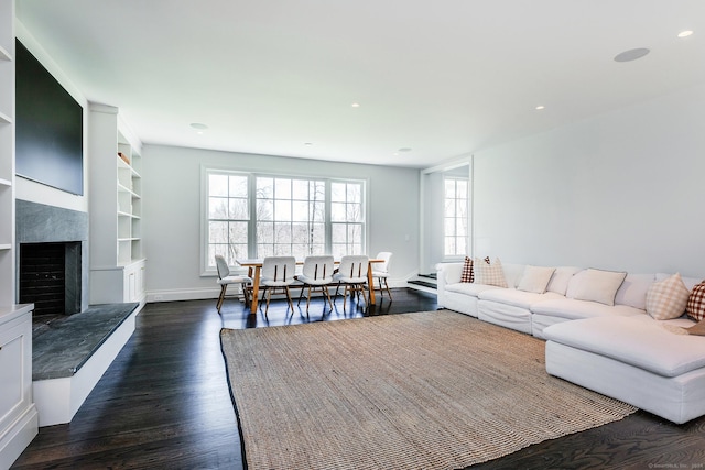 living room with built in features, dark hardwood / wood-style floors, and a healthy amount of sunlight