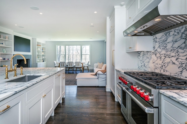 kitchen featuring sink, extractor fan, light stone counters, white cabinetry, and double oven range