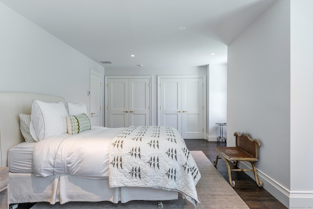 bedroom featuring dark wood-type flooring and multiple closets