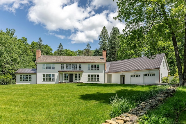 back of house with a garage and a lawn