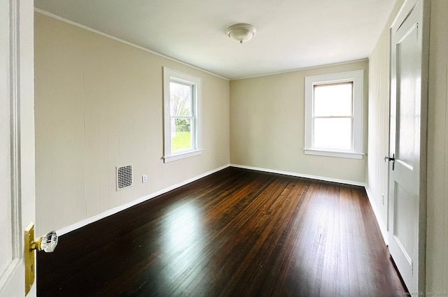 empty room with dark hardwood / wood-style floors and ornamental molding