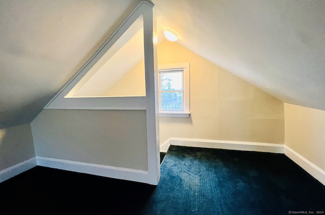 additional living space with dark colored carpet and lofted ceiling