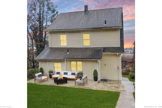 back house at dusk with outdoor lounge area, a patio area, and a yard