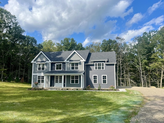 view of front of house featuring gravel driveway, a shingled roof, a porch, board and batten siding, and a front lawn