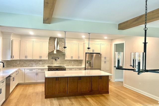 kitchen featuring stainless steel appliances, wall chimney exhaust hood, beamed ceiling, and light hardwood / wood-style flooring