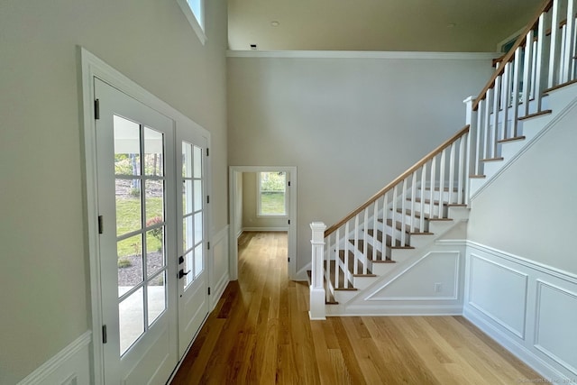 interior space featuring crown molding, a towering ceiling, wood-type flooring, and french doors