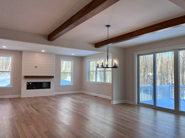 unfurnished living room featuring a fireplace, baseboards, beam ceiling, and wood finished floors