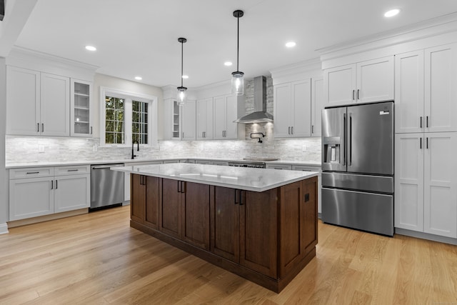 kitchen with white cabinets, glass insert cabinets, appliances with stainless steel finishes, wall chimney range hood, and a sink