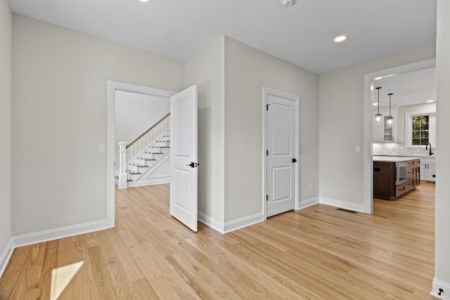 interior space featuring light wood finished floors, stairway, visible vents, and baseboards