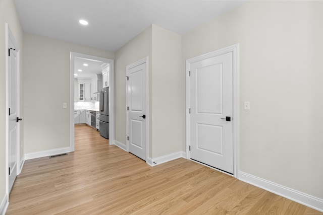 hallway with light wood-type flooring, baseboards, visible vents, and recessed lighting