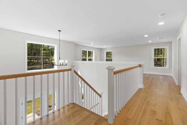 hallway featuring a chandelier, light wood finished floors, an upstairs landing, and recessed lighting