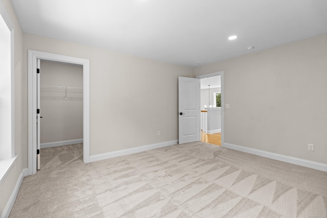 unfurnished bedroom featuring carpet floors, recessed lighting, a spacious closet, and baseboards