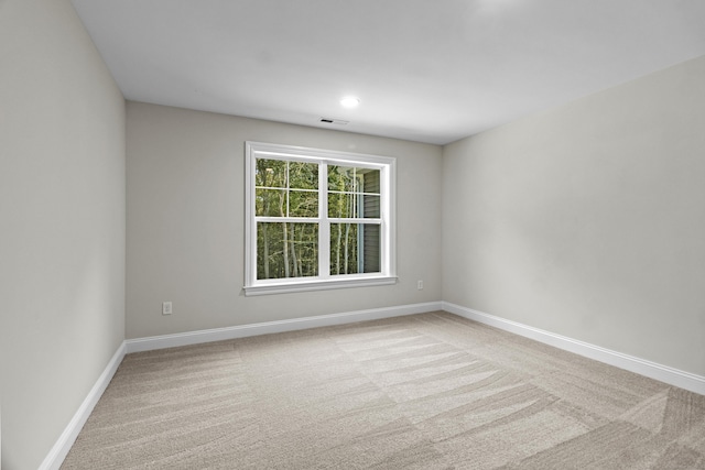 unfurnished room with carpet, visible vents, and baseboards