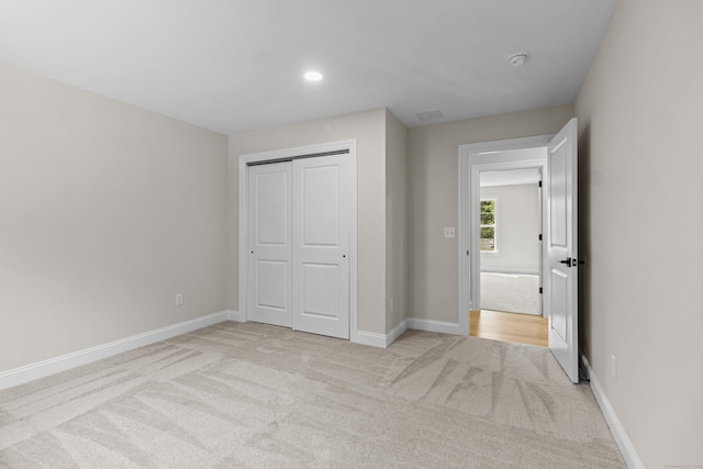 unfurnished bedroom with baseboards, a closet, recessed lighting, and light colored carpet