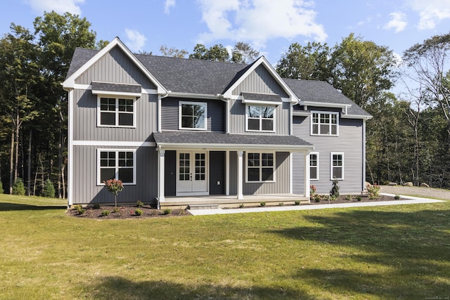 view of front facade featuring a shingled roof, a front yard, covered porch, and french doors