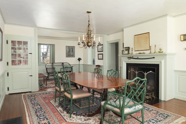 dining space featuring dark wood-type flooring, a chandelier, and ornamental molding