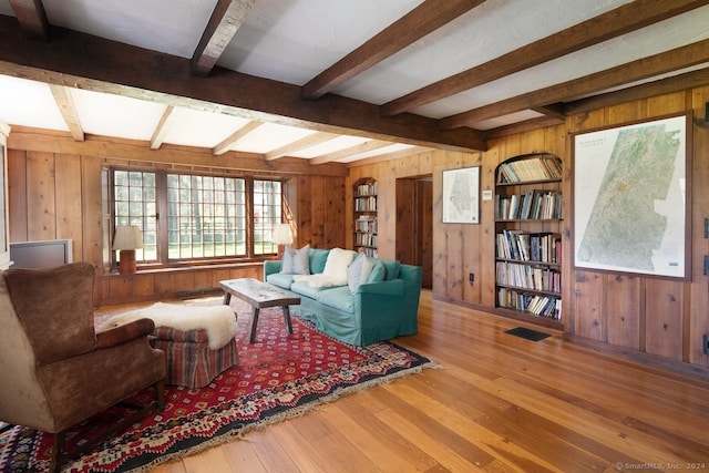 living room featuring hardwood / wood-style flooring, wooden walls, and beam ceiling