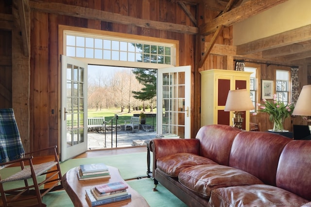 living room featuring high vaulted ceiling, wood walls, and plenty of natural light